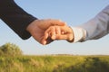 Man and woman hold hands on a background of green trees. In the frame only hands close-up. Royalty Free Stock Photo