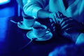 Man and woman hold hands, close up of couple`s arms on wooden table in restaurant with two cups. date in cafe, relations