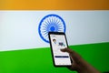 Man woman holding the Co-WIN covid19 coronavirus vaccination tracking app against a flag of India as the innoculation is