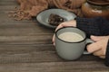 Saucer and dark chocolate on it, brown scarf on the wooden table and woman holding grey cup of milky chocolate drink.Empty space Royalty Free Stock Photo