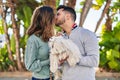 Man and woman holding dog standing together kissing at park Royalty Free Stock Photo