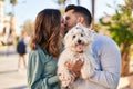 Man and woman holding dog standing together kissing at park Royalty Free Stock Photo