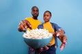 Man and woman holding glass bowl with popcorn and eating snack