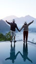 Man and woman holding hands on the edge of the pool with water reflection, raised hand against the mountain with fog at sunrise. Royalty Free Stock Photo