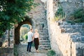 Man and a woman are holding hands near an arch in the ruins of an old castle. Back view Royalty Free Stock Photo