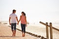 Man, woman and holding hands for walk by the ocean, back view of romantic date and commitment with trust. Love, care and Royalty Free Stock Photo