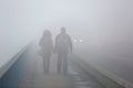 Man and woman holding hands and walking through the fog on street