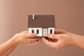 Man and woman holding house model on color background. Mortgage concept Royalty Free Stock Photo