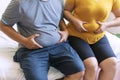 Man and woman holding their big belly while sitting on the bed suffering from extra weight. Couple heavy body size worry