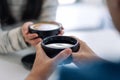 A man and a woman holding two coffee cups together