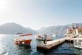 Man and woman hug on the pier against the backdrop of the Perast embankment and boats