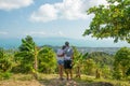 Man and woman hugging at tropical viewpoint looking at breathtaking view, back view