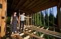 Man and woman inspecting their future wooden frame house nestled in the mountains near forest. Royalty Free Stock Photo