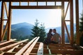 Man and woman inspecting their future wooden frame house nestled in the mountains near forest. Royalty Free Stock Photo