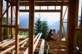 Man and woman inspecting their future wooden frame house nestled in the mountains near forest. Royalty Free Stock Photo