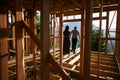 Man and woman inspecting their future wooden frame house nestled in the mountains near forest. Royalty Free Stock Photo