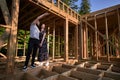 Man and woman inspecting their future wooden frame house nestled in the mountains near forest. Royalty Free Stock Photo