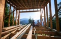 Man and woman inspecting their future wooden frame house nestled in the mountains near forest. Royalty Free Stock Photo