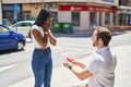 Man and woman interracial couple having engagement proposal at street
