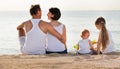 Man and woman with kids sitting with back to camera on beach Royalty Free Stock Photo