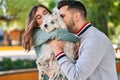 Man and woman kissing dog sitting together at park Royalty Free Stock Photo