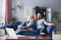 Man and woman with laptop sitting on a blue sofa at home. Young family planning Royalty Free Stock Photo