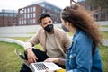 Man and woman with laptop working outdoors in park in city, coronavirus concept. Royalty Free Stock Photo