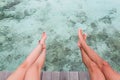 Man and woman legs seated on a pier over clear blue water Royalty Free Stock Photo