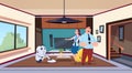 Man And Woman Looking At Robot Housekeeper Cleaning Living Room