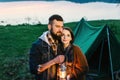 Man and woman lovers hold a flashlight at dawn near the lake