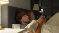 Man and woman lying in bed each with smartphone and tablet pc. problems in marriage and intersexual relationship