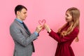 man and woman make a heart of Christmas striped candies on a pink background celebrate Valentine\'s Day
