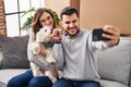 Man and woman make selfie by the smartphone sitting on sofa with dog at new home Royalty Free Stock Photo