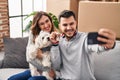 Man and woman make selfie by the smartphone sitting on sofa with dog at new home Royalty Free Stock Photo