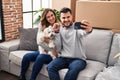 Man and woman make selfie by the smartphone sitting on sofa with dog at new home Royalty Free Stock Photo