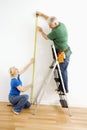 Man and woman measuring wall.