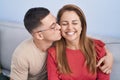 Man and woman mother and son hugging each other and kissing sitting on sofa at home Royalty Free Stock Photo