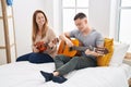 Man and woman mother and son playing classical guitar and ukulele at bedroom Royalty Free Stock Photo