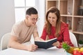 Man and woman mother and son reading book sitting on table at home Royalty Free Stock Photo