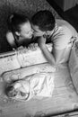Man and a woman near their newborn. Parents kiss. Boy cries in his crib. Mom, dad and baby. Portrait of young family. Family life