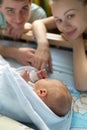 Man and a woman near their newborn. Parents look at the camera. Boy sleeping in his crib. Mom, dad and baby. Portrait of young Royalty Free Stock Photo