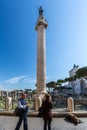 A man and woman next to a beggar in front of the famous Trajan`s Column in Rome.