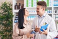 Man and woman pharmacist and client using smartphone and touchpad at pharmacy Royalty Free Stock Photo