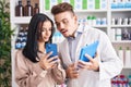Man and woman pharmacist and client using smartphone and touchpad at pharmacy Royalty Free Stock Photo