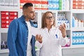 Man and woman pharmacist reading pills label bottle and prescription at pharmacy