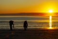 A man and a woman are photographing the sunrise on a beach Royalty Free Stock Photo