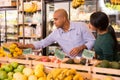 Man and woman picking ripe fruits and vegetables together at supermarket