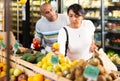 Man and woman picking ripe fruits and vegetables together at supermarket Royalty Free Stock Photo