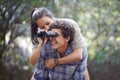 Man, woman and piggyback in forest with binocular for travel, adventure or sightseeing in nature with happiness. Couple