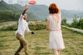 Man and woman playing frisbee in a park next to a river and forest ridge Royalty Free Stock Photo